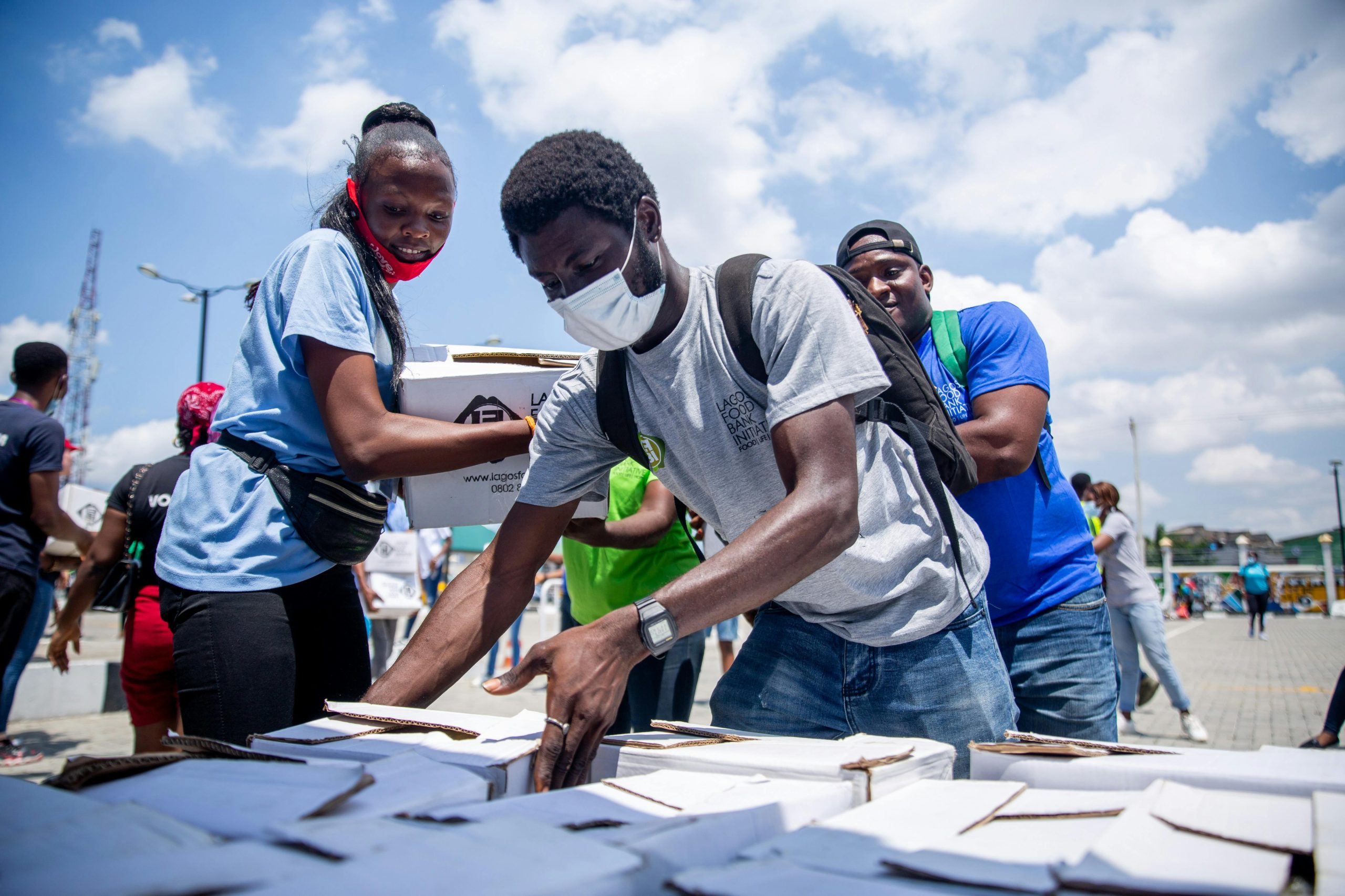 Volunteers distribute aid packages during a charitable event in an outdoor setting.